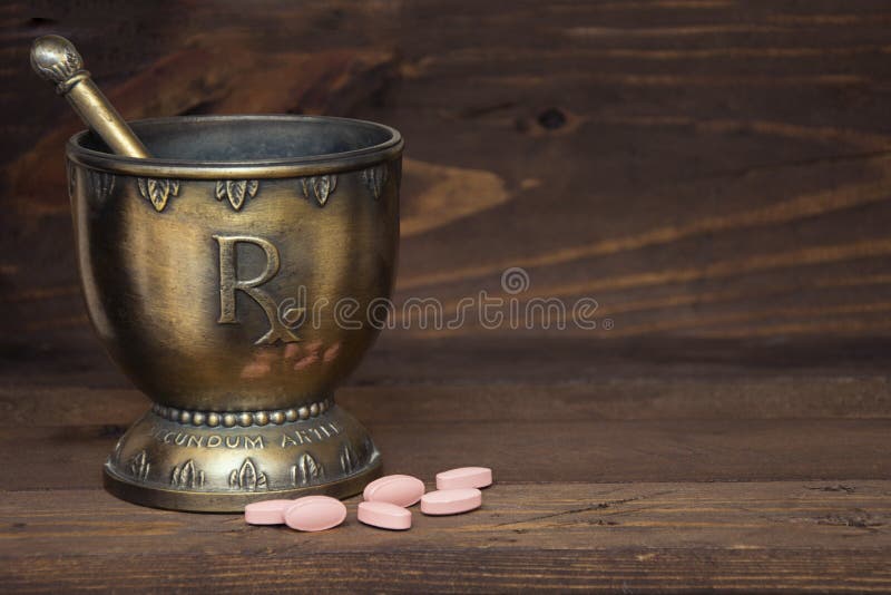 RX mortar and pestle with pink tablets on wood background