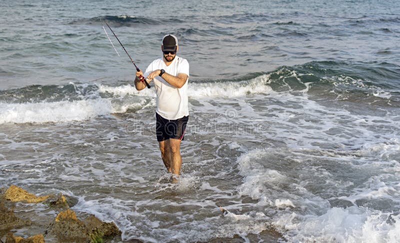 Rybak pozycja przy seashore haczy ryby zdjęcie stock Rybak pozycja przy seashore haczy ryby zdjęcie stock