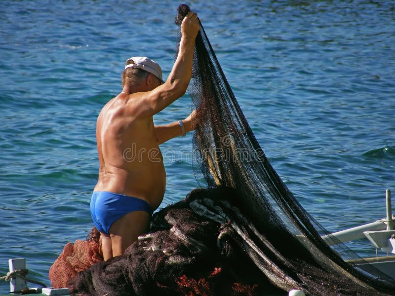 2. September 2010. Omis (Croatia) The old fisherman in bikini pulls from the Adriatic Sea net hunted for fish. In Croatia (Dalmatia) people who live near the sea with their small wooden boats catch fish. It's a tradition since Omis famous city by fish, fishing. 2. September 2010. Omis (Croatia) The old fisherman in bikini pulls from the Adriatic Sea net hunted for fish. In Croatia (Dalmatia) people who live near the sea with their small wooden boats catch fish. It's a tradition since Omis famous city by fish, fishing