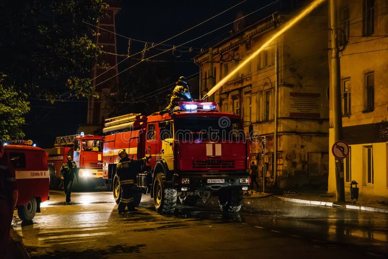 Rybinsk, Russia -31 luglio 2018: I pompieri con la manichetta antincendio ed autopompe antincendio o camion stanno combattendo il fotografia stock libera da diritti Rybinsk, Russia -31 luglio 2018: I pompieri con la manichetta antincendio ed autopompe antincendio o camion stanno combattendo il fotografia stock libera da diritti