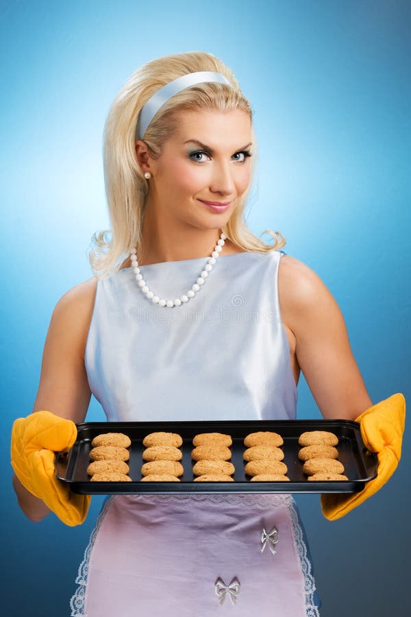 Beautiful woman holding hot roasting pan with oat cookies on it. Retro stylized portrait. Beautiful woman holding hot roasting pan with oat cookies on it. Retro stylized portrait