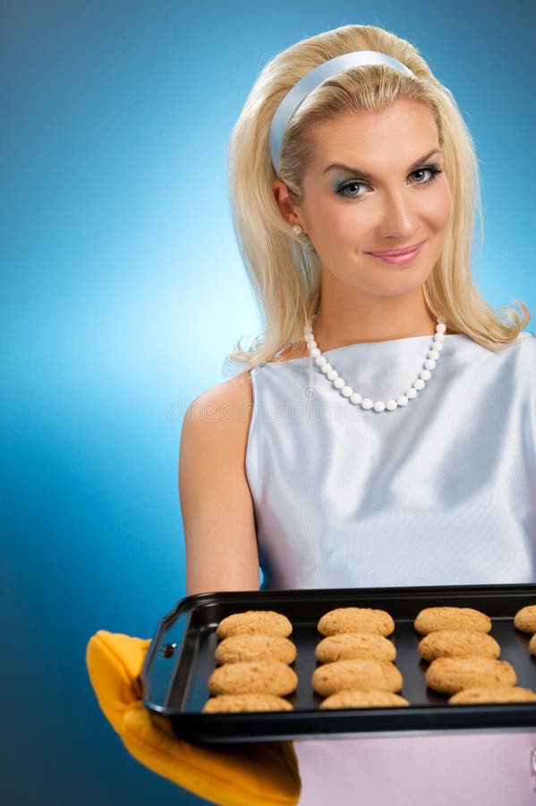 Beautiful woman holding hot roasting pan with oat cookies on it. Retro stylized portrait. Beautiful woman holding hot roasting pan with oat cookies on it. Retro stylized portrait