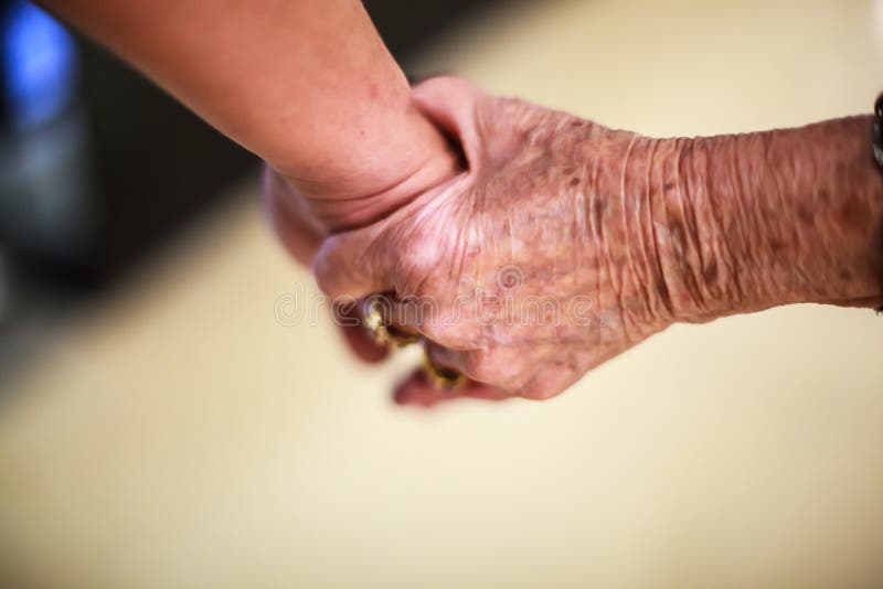 Rynkig äldre hand för kvinna` som s rymmer till handen för ` s för ung man som går i shoppinggalleria Familjförhållande, hälsa, h royaltyfri fotografi Rynkig äldre hand för kvinna` som s rymmer till handen för ` s för ung man som går i shoppinggalleria Familjförhållande, hälsa, h royaltyfri fotografi