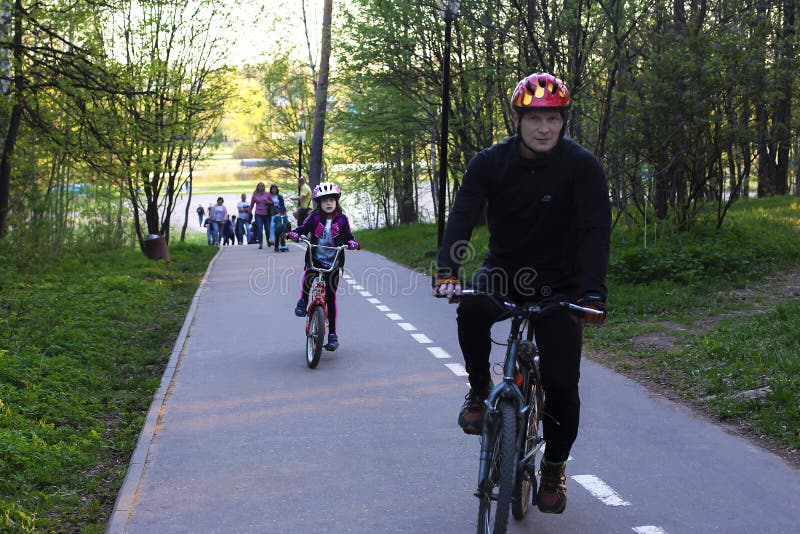 Ryssland Moskva, kan 12-, 2018-, fader- och dotterridningcyklar i parkera, ledare royaltyfria foton Ryssland Moskva, kan 12-, 2018-, fader- och dotterridningcyklar i parkera, ledare royaltyfria foton