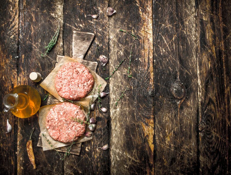 Rå hamburgare från nötkött med kryddor och olivolja royaltyfri bild Rå hamburgare från nötkött med kryddor och olivolja royaltyfri bild