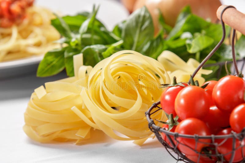 Rå italiensk tagliatellepasta och körsbärsröda tomater royaltyfria bilder Rå italiensk tagliatellepasta och körsbärsröda tomater royaltyfria bilder