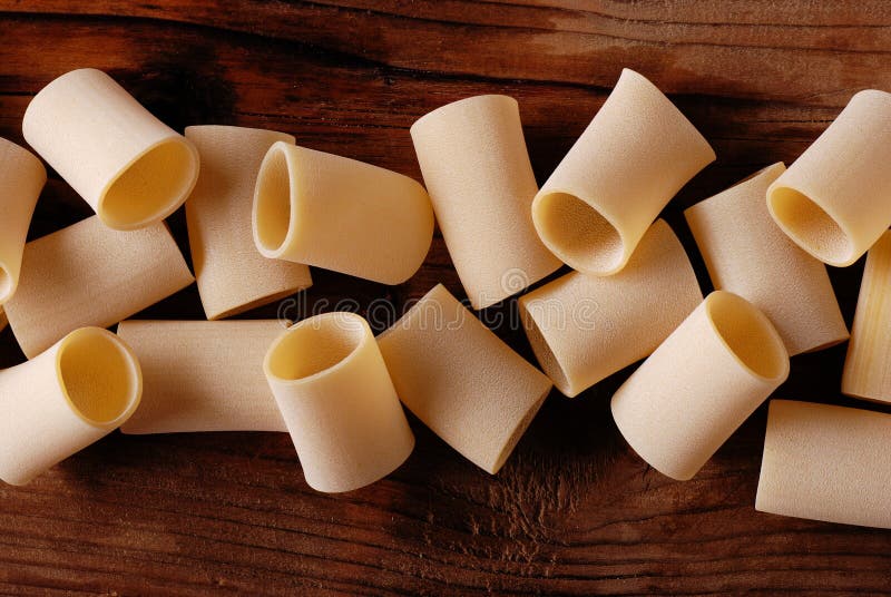 Paccheri raw on the wooden table, traditional Neapolitan pasta. Paccheri raw on the wooden table, traditional Neapolitan pasta