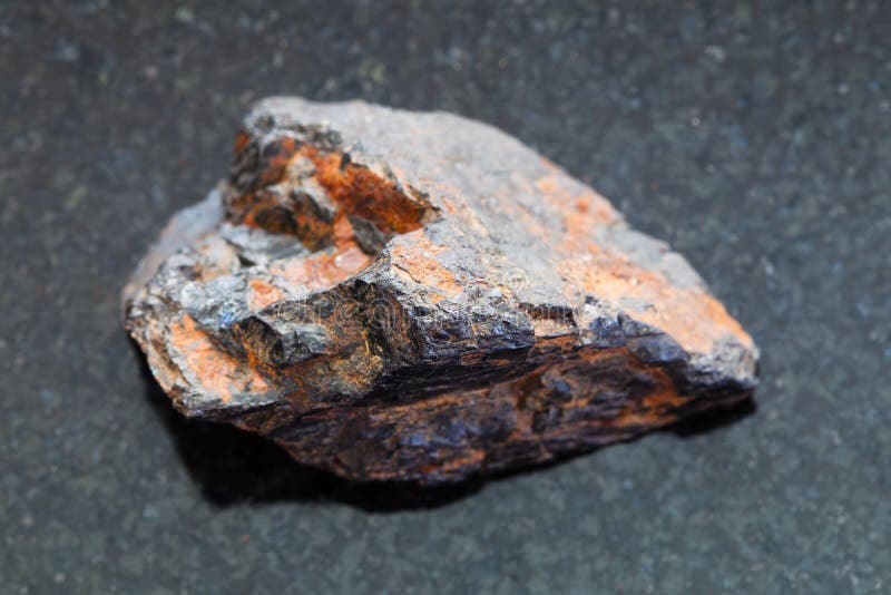 Rå Wolframitesten (volframmalm) på mörker. Makroskytte av naturlig mineral vaggar provet - den rå Wolframitestenen (volframmalm) på mörk granitbakgrund från Zabaykalsky Krai av Ryssland