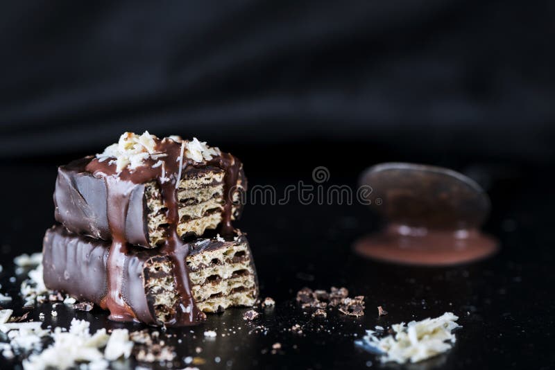 Rån med smältt bitter choklad och vita chokladstänk, slut upp, mörk bakgrund arkivfoton Rån med smältt bitter choklad och vita chokladstänk, slut upp, mörk bakgrund arkivfoton