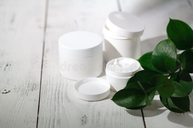 Récipients cosmétiques de bouteille avec les feuilles de fines herbes vertes, label vide image stock Récipients cosmétiques de bouteille avec les feuilles de fines herbes vertes, label vide image stock