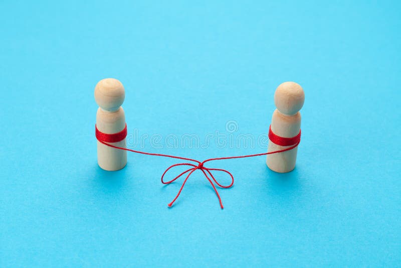 Reconciliation in relationships. Two figures of people are connected by a thread on a blue background. Married couple. Reconciliation in relationships. Two figures of people are connected by a thread on a blue background. Married couple.