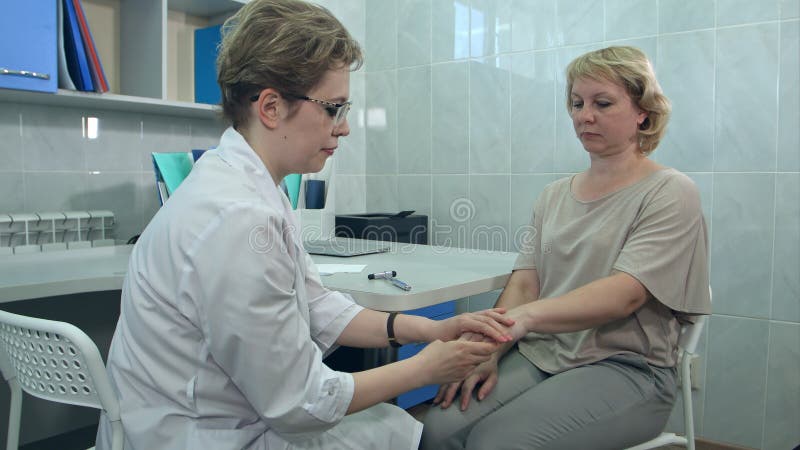 Réflexe de genou d'essai de neurologue sur un patient féminin à l'aide d'un marteau photographie stock Réflexe de genou d'essai de neurologue sur un patient féminin à l'aide d'un marteau photographie stock