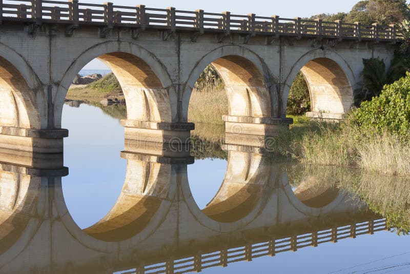 Réflexion d'un pont de chemin de fer croisant une lagune sur la côte sud de KZN de l'Afrique du Sud image stock
