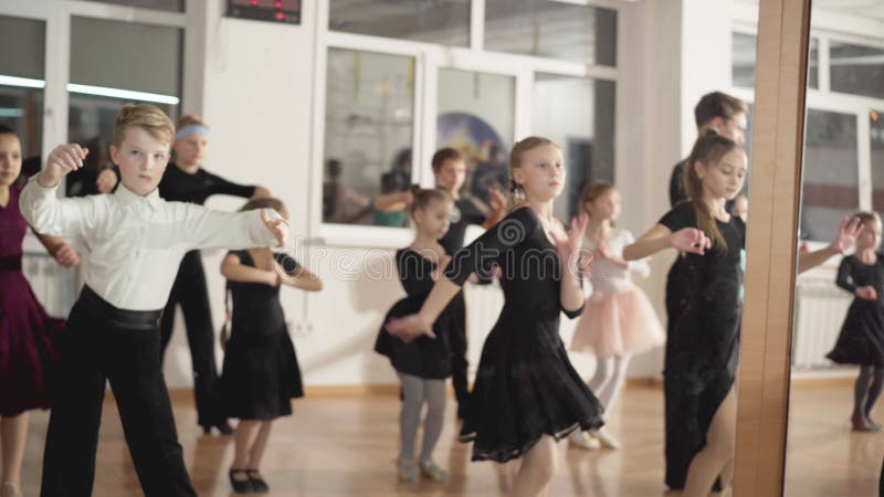 Réflexion dans le miroir du groupe d'enfants répétant les mouvements latins de salle de bal avec enseignant marchant. talentueux c clips vidéos