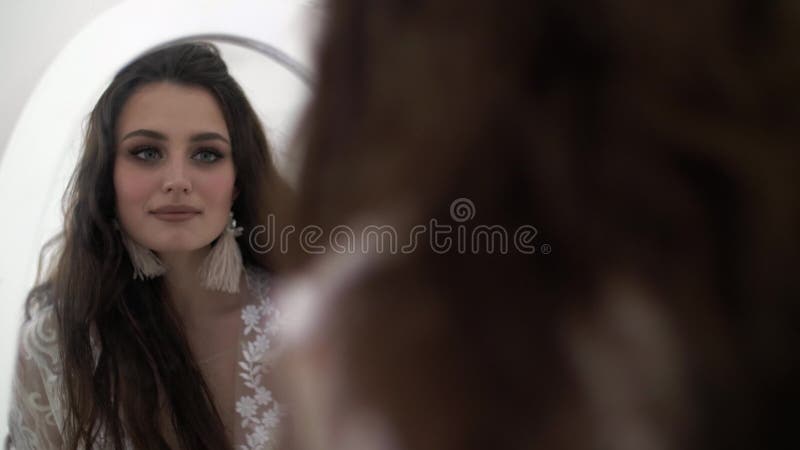 Réflexion dans le miroir La belle jeune femme de brune regarde dans le miroir et les rires banque de vidéos