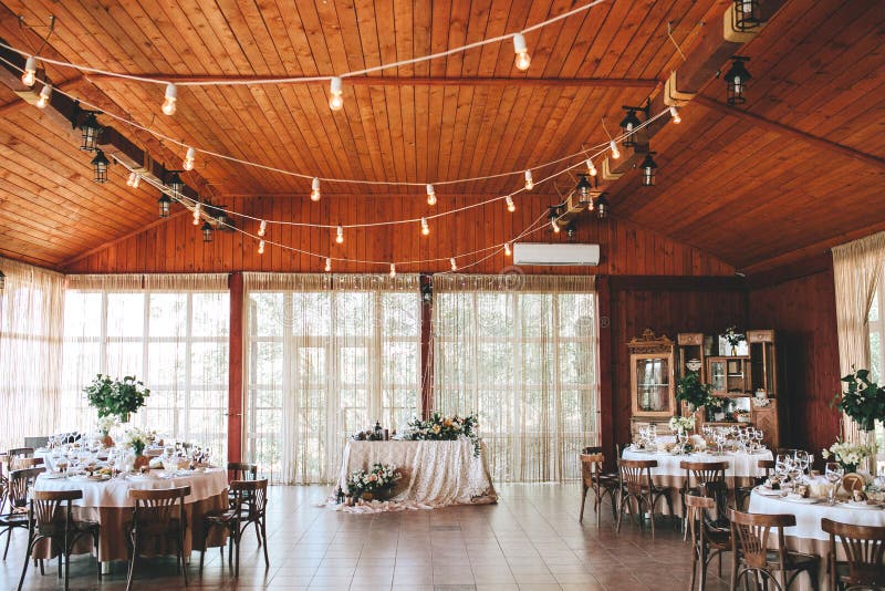 Régalez le hall en bois pour un mariage rustique avec les tables décorées rondes, chaises viennoises avec les feuilles fleuries e photos stock Régalez le hall en bois pour un mariage rustique avec les tables décorées rondes, chaises viennoises avec les feuilles fleuries e photos stock