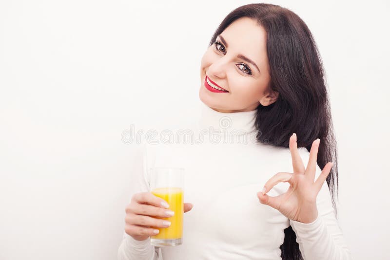 Régime Une belle jeune fille qui suit le chiffre, buvant du jus d'orange Le concept de la consommation saine Fond blanc images stock Régime Une belle jeune fille qui suit le chiffre, buvant du jus d'orange Le concept de la consommation saine Fond blanc images stock