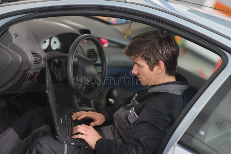 Réparation de la voiture avec l'ordinateur photographie stock Réparation de la voiture avec l'ordinateur photographie stock