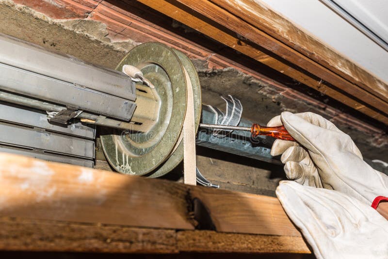 Réparation de volet de roulement Le travailleur ajuste un volet cassé de rouleau d'une maison photo stock Réparation de volet de roulement Le travailleur ajuste un volet cassé de rouleau d'une maison photo stock