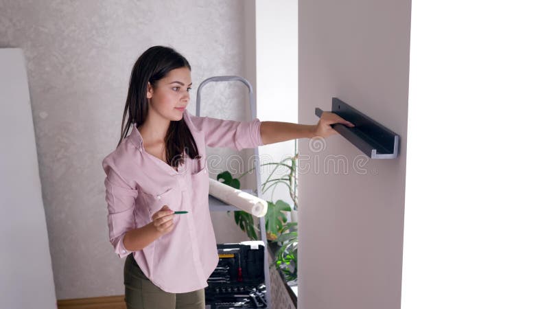 Réparez l'appartement, la belle femme fait refaire et accroche l'étagère sur le mur pendant la rénovation de la maison