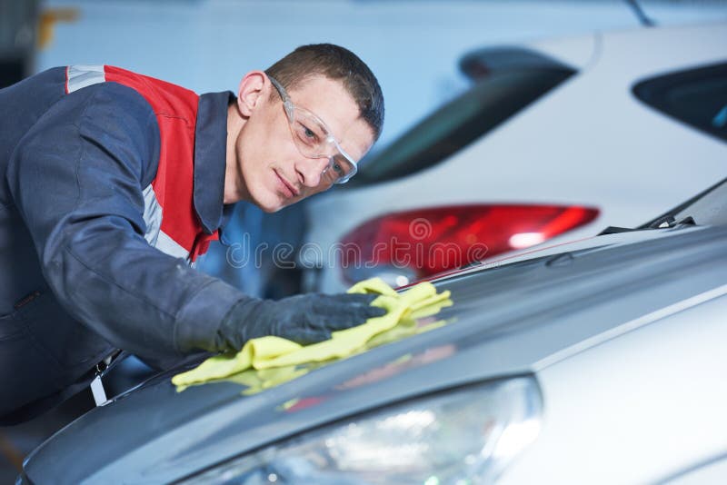 Auto repairing works. Repair man worker polishing automobile car body after painting or buffing in garage. Auto repairing works. Repair man worker polishing automobile car body after painting or buffing in garage