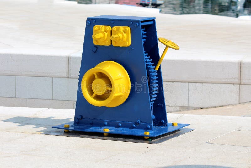 Rétro bleu reconstitué de cru et roue jaune de poulie de fonte montés sur le pilier en pierre traditionnel de tuiles utilisé pour image libre de droits Rétro bleu reconstitué de cru et roue jaune de poulie de fonte montés sur le pilier en pierre traditionnel de tuiles utilisé pour image libre de droits