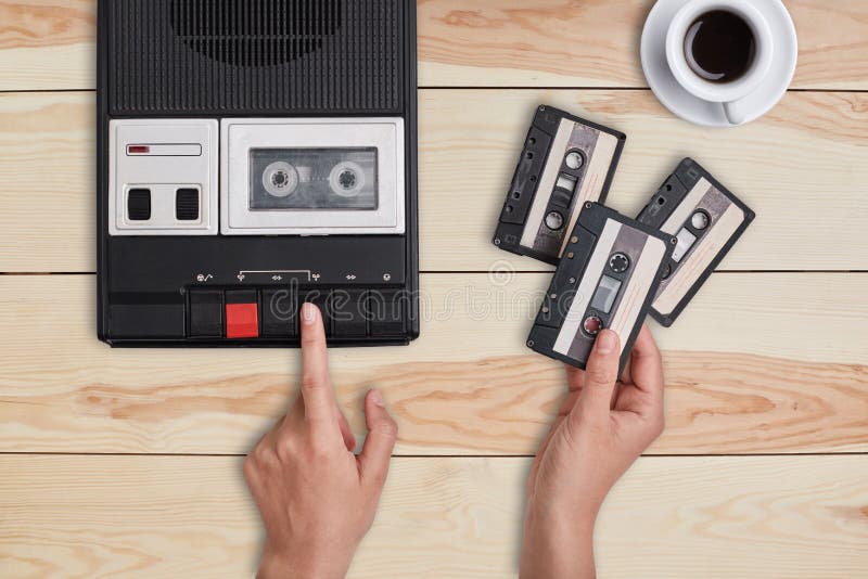 Rétro substance, vieux articles, souvenirs Mains alimentant le vieux magnétophone à cassettes de bande et tenant trois cassettes photographie stock Rétro substance, vieux articles, souvenirs Mains alimentant le vieux magnétophone à cassettes de bande et tenant trois cassettes photographie stock