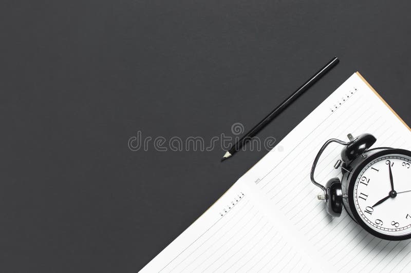 Réveil noir étendu par appartement, journal intime ouvert propre de carnet, crayon sur l'espace foncé gris de copie de vue supéri image libre de droits Réveil noir étendu par appartement, journal intime ouvert propre de carnet, crayon sur l'espace foncé gris de copie de vue supéri image libre de droits