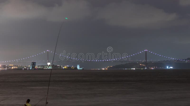 Río tagus y el 25 de abril puente o ponte 25 de abril iluminado por la noche en lisboa portugal. almacen de metraje de vídeo