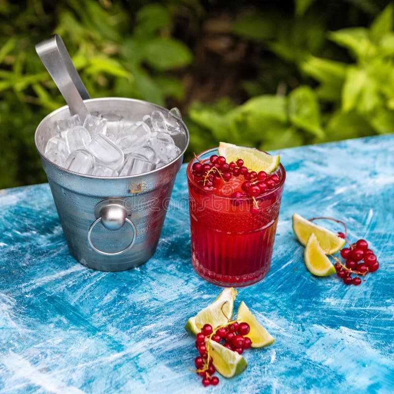 Röd drink med is. Röd coctail med grön bakgrund