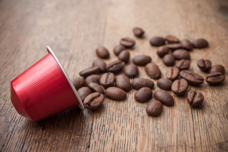 röd espressokaffekapsel med kaffebönor på trä royaltyfri foto röd espressokaffekapsel med kaffebönor på trä royaltyfri foto