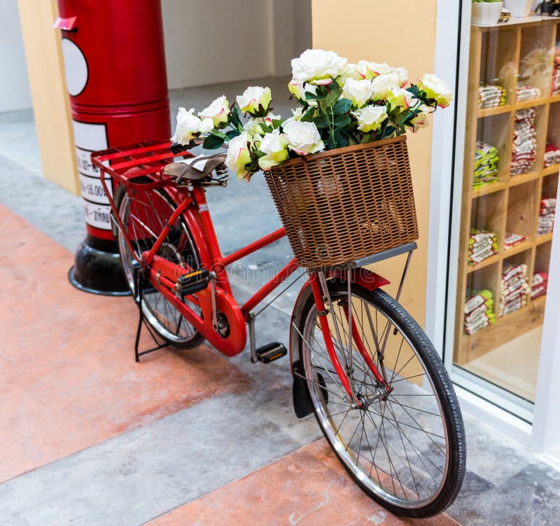 Röd målad cykel med en hink av vita blommor arkivfoto Röd målad cykel med en hink av vita blommor arkivfoto