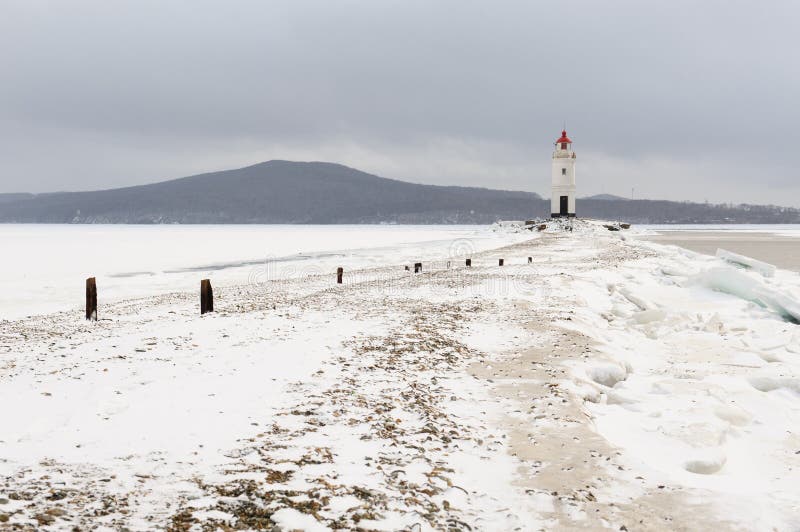 Röd och vit fyr på den snöig havskusten för vinter arkivbilder Röd och vit fyr på den snöig havskusten för vinter arkivbilder