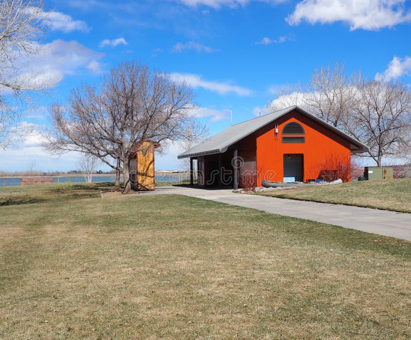 Red pole barn by a lake and grass area. Red pole barn by a lake and grass area