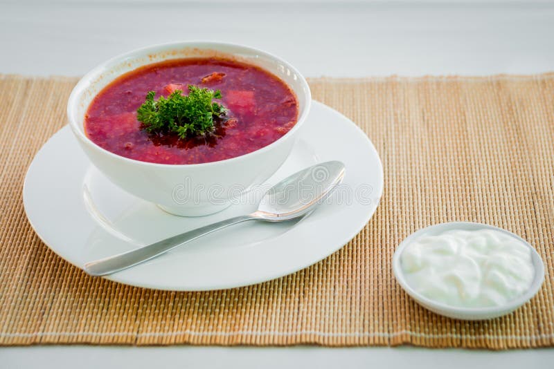 Röd soppa med sur kräm på den vita plattan.