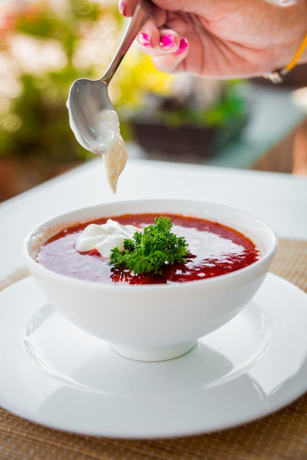 Röd soppa med sur kräm på den vita plattan.