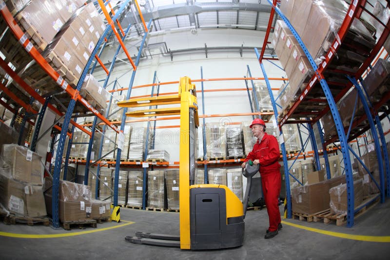 Worker in red uniform at work in warehouse - fish eye lens. Worker in red uniform at work in warehouse - fish eye lens