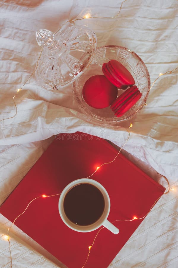 Röda macarons i kristallbunke, bok och ett kaffe arkivfoto Röda macarons i kristallbunke, bok och ett kaffe arkivfoto