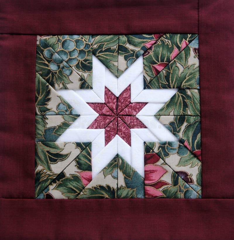 Quilted star in white with colorful fabrics and a maroon border. Quilted star in white with colorful fabrics and a maroon border