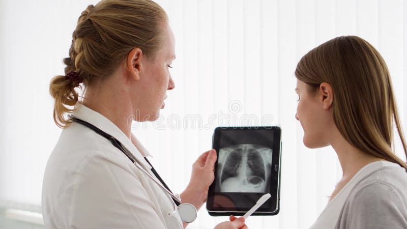 Röntgenstråle för kvinnaläkarevisning på minnestavlan till den kvinnliga patienten i klinik Kvinnlig yrkesmässig doktor på arbete