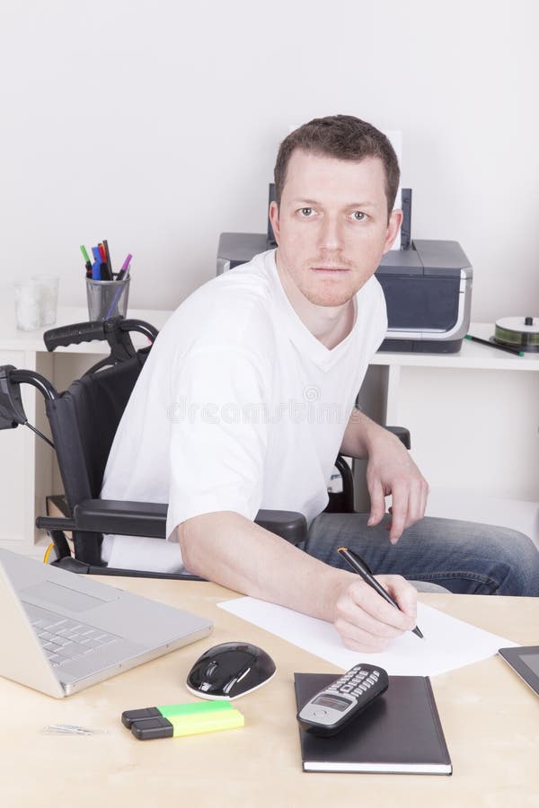 Young disabled man in wheelchair working in a home Office. Young disabled man in wheelchair working in a home Office.