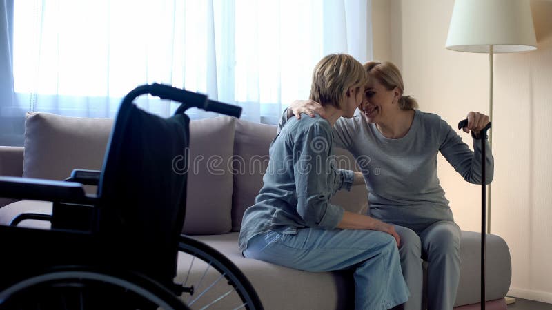 Rörelsehindrad moder som sitter på soffan och talar till dottern, familjservice, omsorg fotografering för bildbyråer Rörelsehindrad moder som sitter på soffan och talar till dottern, familjservice, omsorg fotografering för bildbyråer