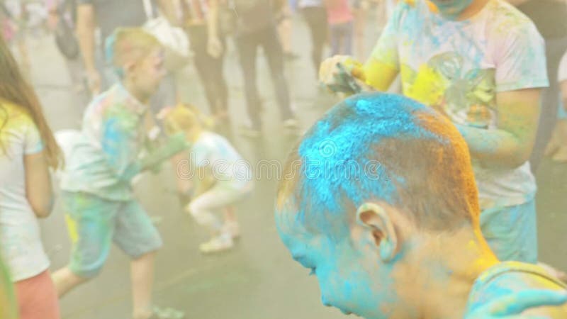 RÚSSIA, IRKUTSK - 27 DE JUNHO DE 2018: Jovens felizes que dançam e que comemoram durante o festival de Holi das cores Multidão de