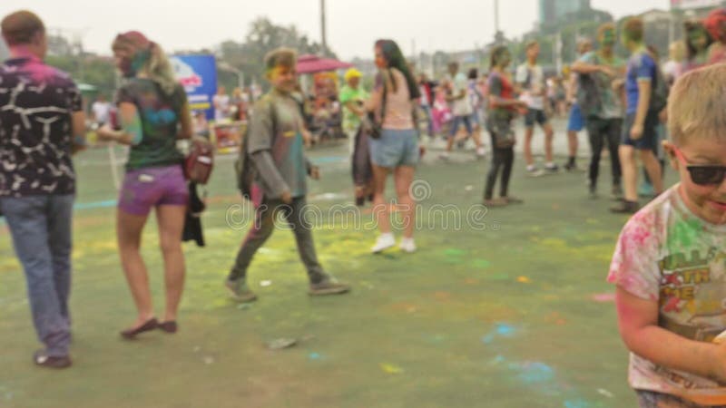 RÚSSIA, IRKUTSK - 27 DE JUNHO DE 2018: Jovens felizes que dançam e que comemoram durante o festival de Holi das cores Multidão de