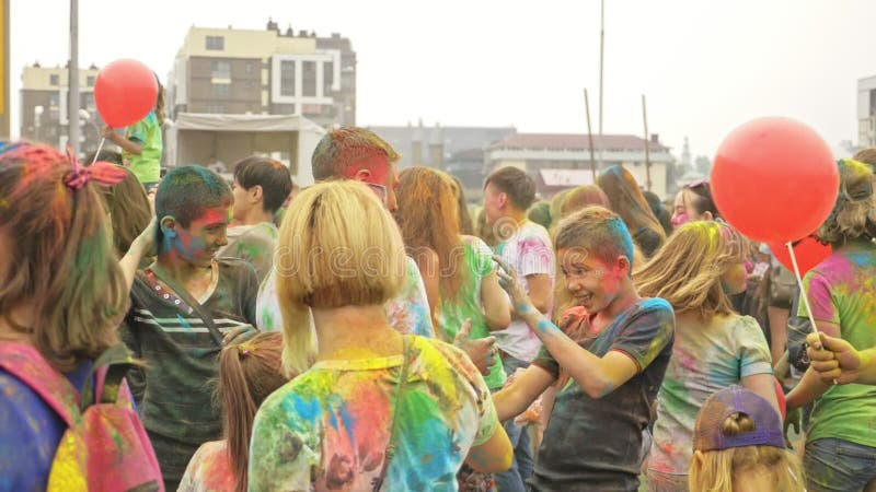 RÚSSIA, IRKUTSK - 27 DE JUNHO DE 2018: Jovens felizes que dançam e que comemoram durante o festival de Holi das cores Multidão de