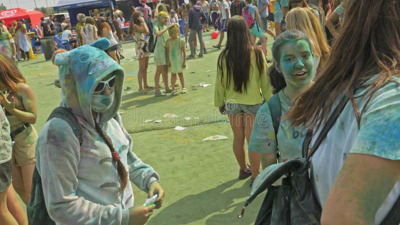 RÚSSIA, IRKUTSK - 27 DE JUNHO DE 2018: Jovens felizes que dançam e que comemoram durante o festival de Holi das cores Multidão de