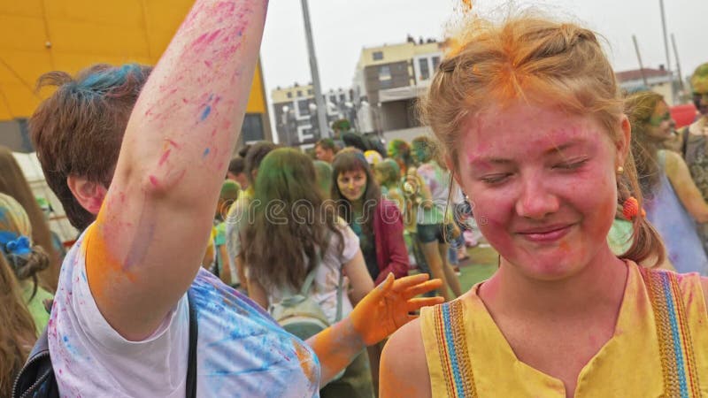 RÚSSIA, IRKUTSK - 27 DE JUNHO DE 2018: Jovens felizes que dançam e que comemoram durante o festival de Holi das cores Multidão de