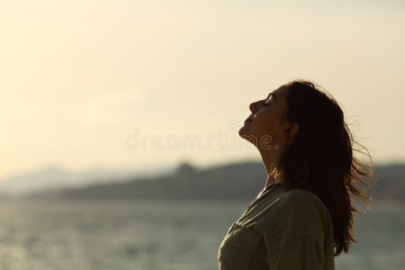 Profile of a back light of woman silhouette breathing deep fresh air on the beach. Profile of a back light of woman silhouette breathing deep fresh air on the beach