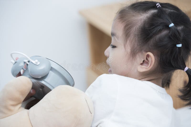 Rückseite des asiatischen Mädchens legen auf Bett- und Handspiel mit Uhr stockbild Rückseite des asiatischen Mädchens legen auf Bett- und Handspiel mit Uhr stockbild