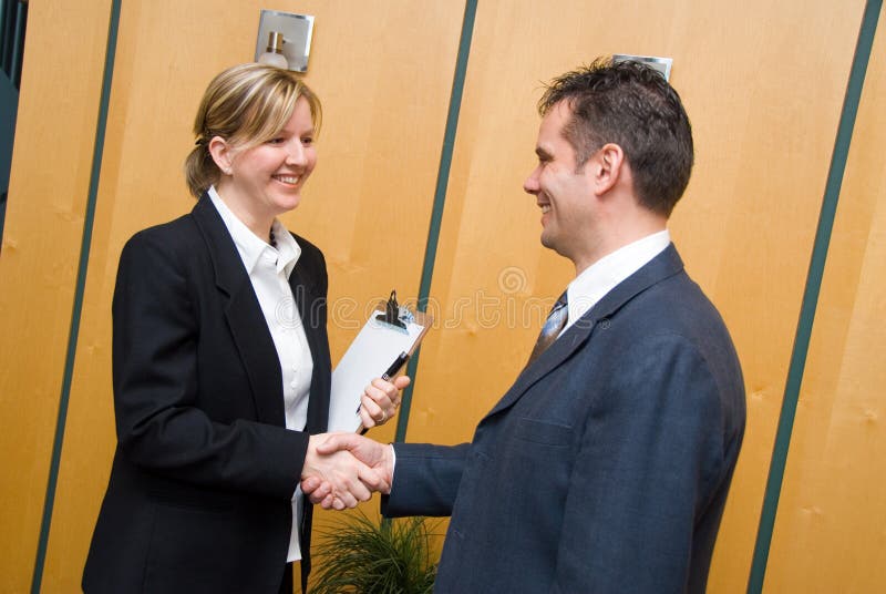 Man and woman greeting each other in a reception area. Man and woman greeting each other in a reception area